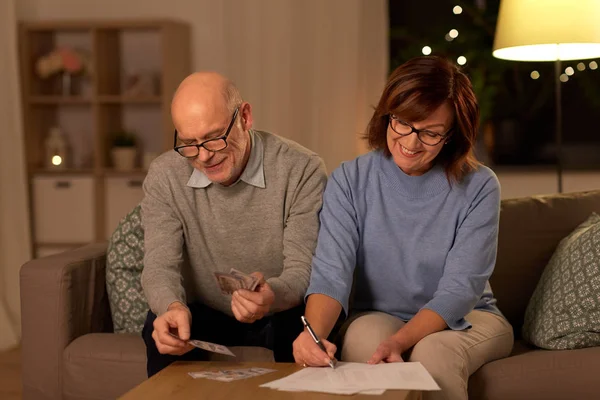 Senior couple with bills counting money at home — Stock Photo, Image