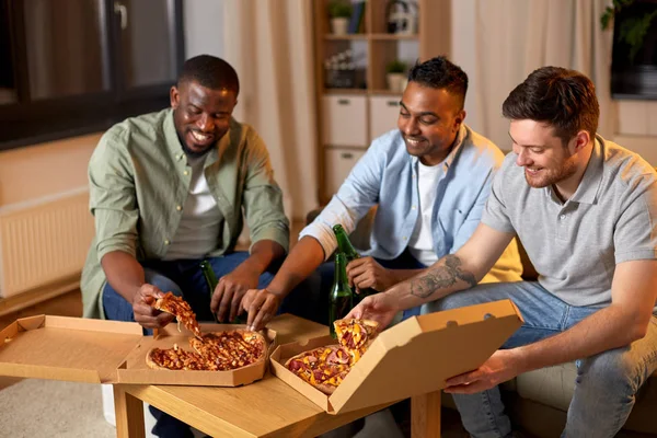 Amici maschi felici con birra mangiare pizza a casa — Foto Stock