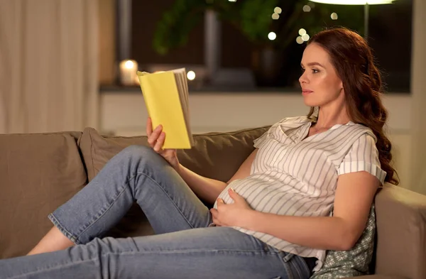 Glücklich lächelnde schwangere Frau liest Buch zu Hause — Stockfoto