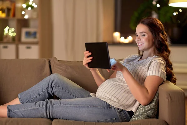 Heureuse femme enceinte avec tablette pc à la maison — Photo