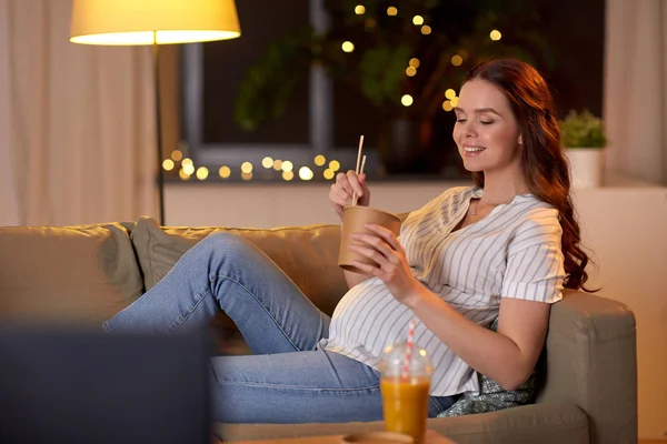 Mujer embarazada viendo la televisión y comiendo wok en casa — Foto de Stock