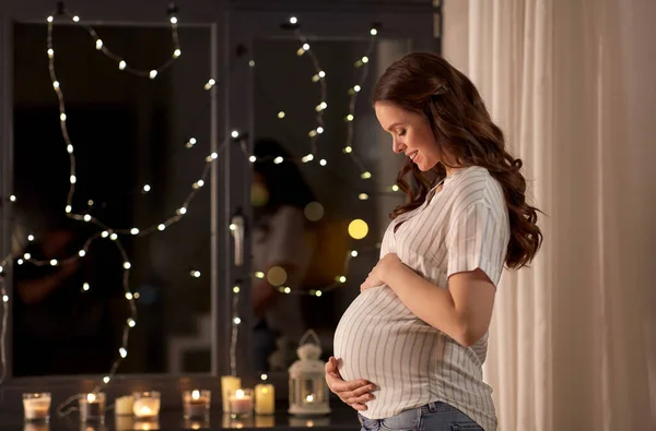 Mulher grávida feliz olhando para fora da janela em casa — Fotografia de Stock