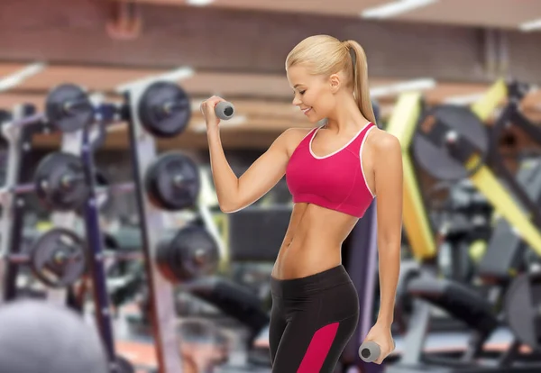 Glad ung kvinna med hantlar som tränar på gym — Stockfoto