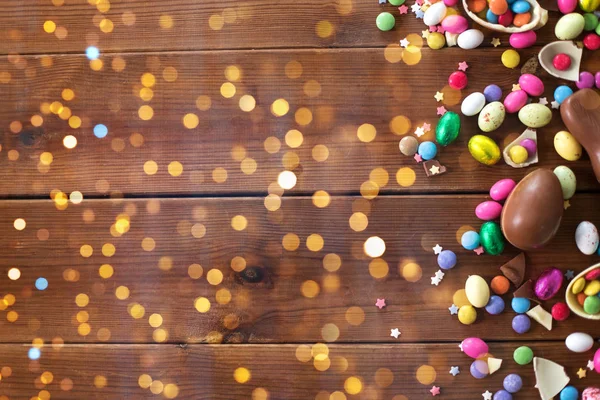 Huevos de chocolate y gotas de caramelo en mesa de madera —  Fotos de Stock