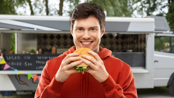 Šťastný mladý muž jíst hamburger v jídelním voze — Stock fotografie