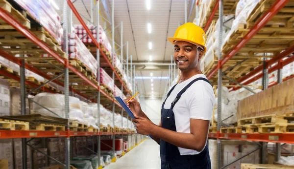 Happy worker or loader with clipboard at warehouse — Stock Photo, Image