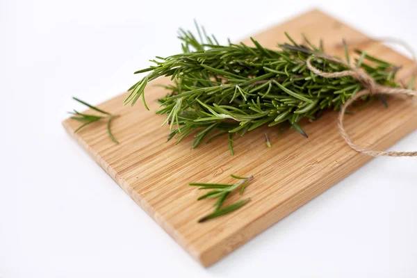 Bunch of rosemary on wooden cutting board — Stock fotografie