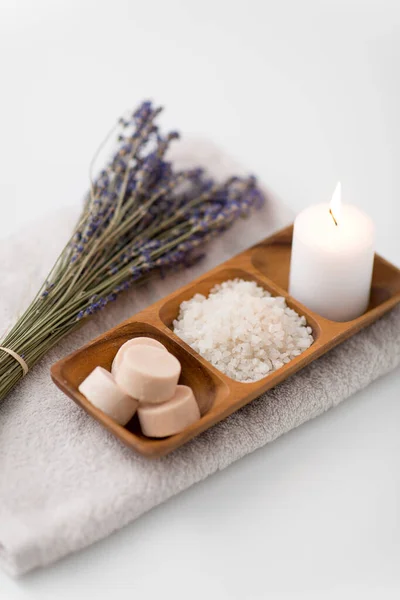 Havssalt, tvål, ljus och lavendel på badhandduk — Stockfoto