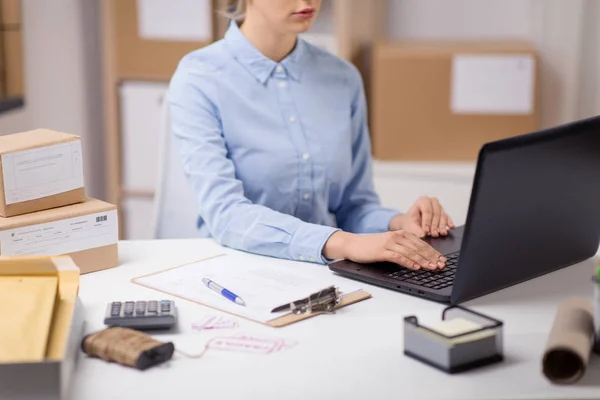 Femme avec ordinateur portable et presse-papiers au bureau de poste — Photo