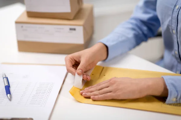 Femme enlever l'autocollant de l'enveloppe avec le colis — Photo