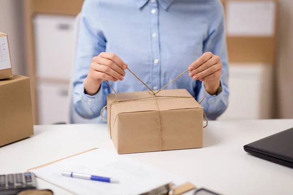 Frau packt Paket und bindet Seil bei Post — Stockfoto