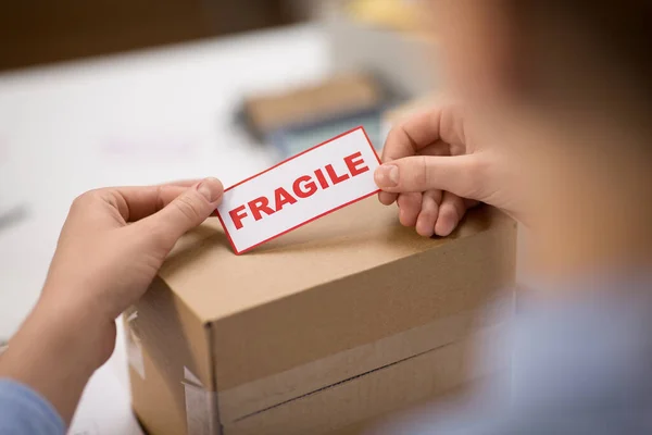 Woman sticking fragile mark to parcel box — Stock Photo, Image