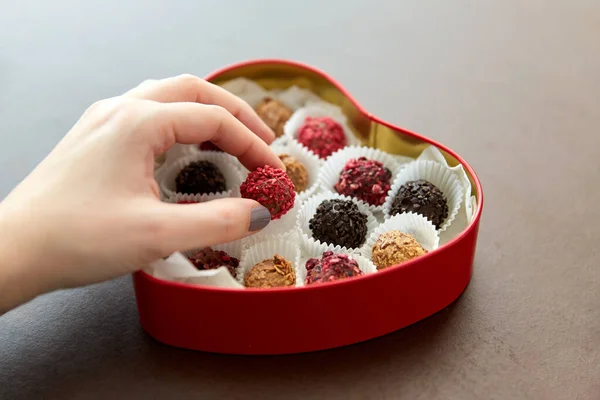 Ręka z cukierkami w kształcie serca pudełko czekolady — Zdjęcie stockowe