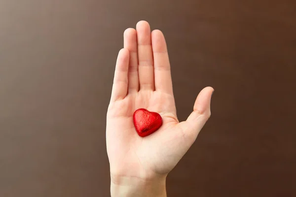 Ręka w kształcie czerwonego serca cukierki czekoladowe — Zdjęcie stockowe