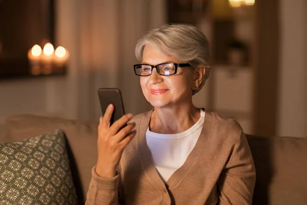 Mulher sênior feliz com smartphone em casa — Fotografia de Stock