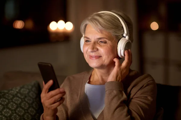 Старшая женщина в наушниках слушает музыку — стоковое фото