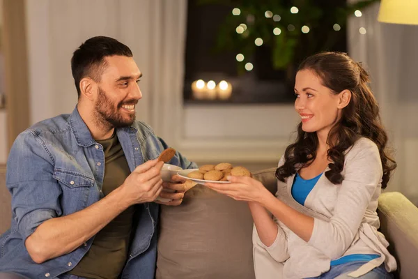 Feliz pareja bebiendo té con galletas en casa — Foto de Stock