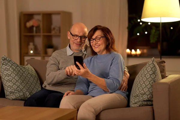 Heureux couple aîné avec smartphone à la maison — Photo