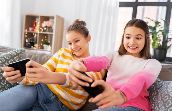 Meninas e jogar jogo em smartphones em casa — Fotografia de Stock