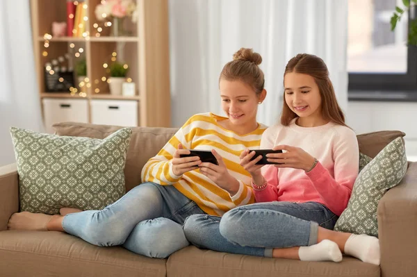Щасливі дівчата-підлітки зі смартфонами вдома — стокове фото