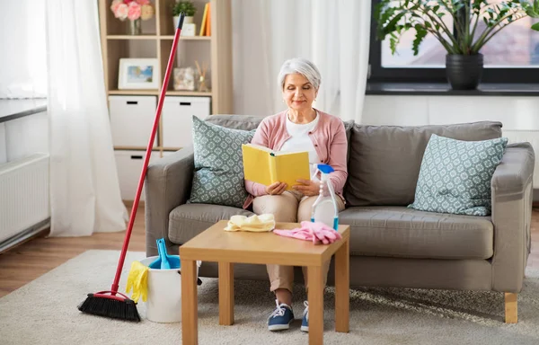 Старша жінка читає книгу після прибирання вдома — стокове фото