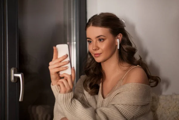 Femme avec smartphone et écouteurs à la maison — Photo