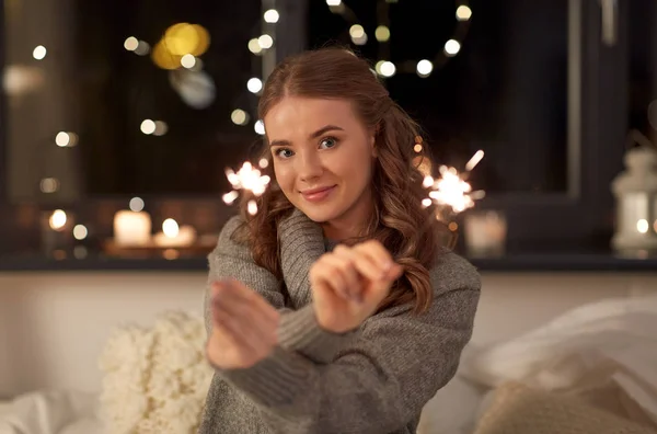 快乐的年轻女人，家里床上放着火花 — 图库照片