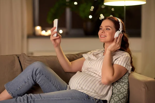 Schwangere mit Smartphone und Kopfhörer — Stockfoto