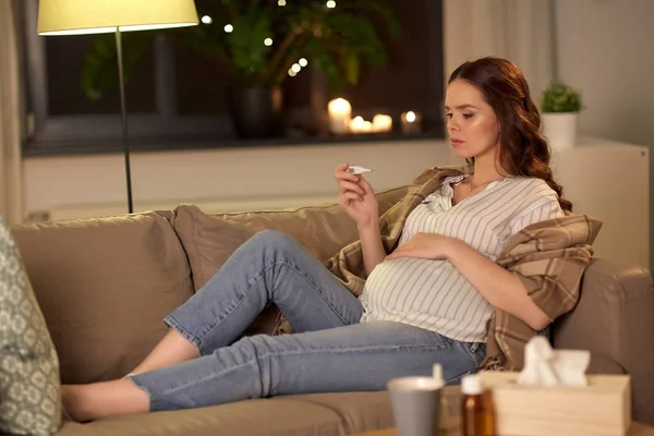 Mujer embarazada enferma con termómetro en casa —  Fotos de Stock