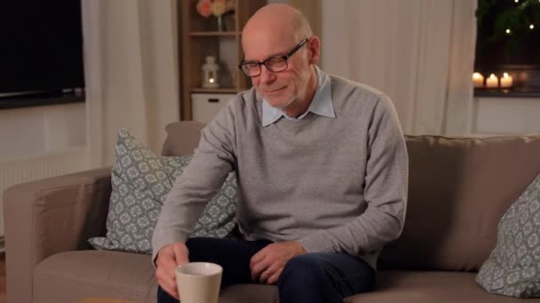 Happy senior man drinking tea at home in evening — Stock Video