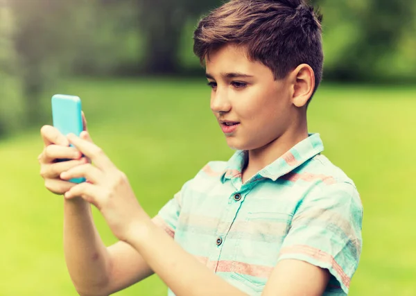 Мальчик со смартфоном играет в игру в летнем парке — стоковое фото