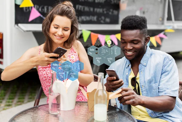 Paar mit Smartphones isst Wok im Food-Truck — Stockfoto