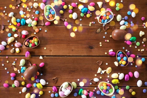 Chocolate eggs and candy drops on wooden table — Stock Photo, Image
