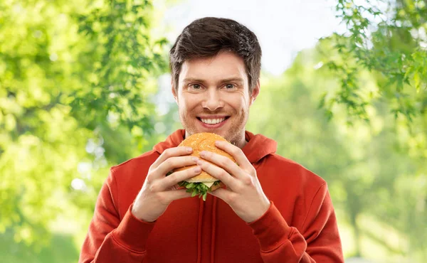 幸せな若い男を食べるハンバーガー — ストック写真