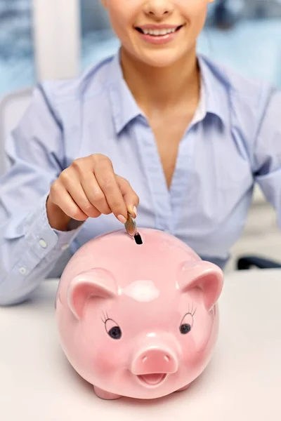 Empresária com banco porquinho e moeda no escritório — Fotografia de Stock