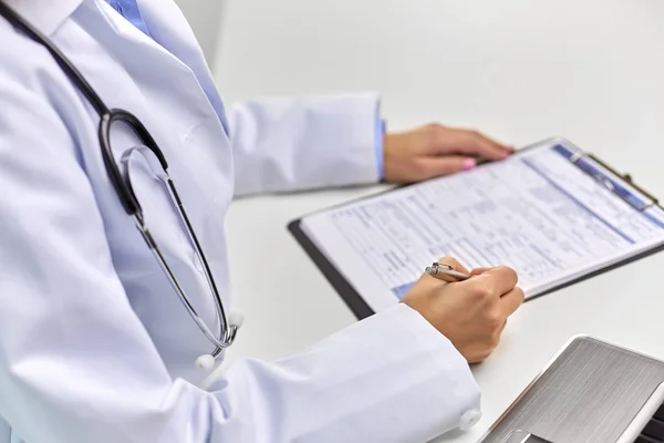 Close up of female doctor writing medical report — Stock Photo, Image