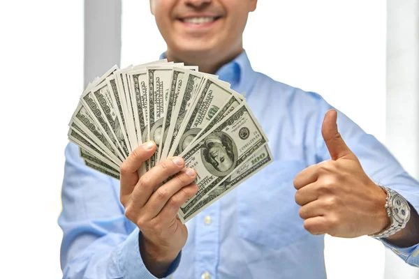 Улыбающийся бизнесмен с деньгами показывает большие пальцы вверх — стоковое фото