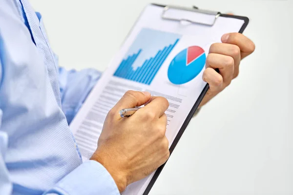 Hands of businessman holding clipboard with charts — Stock Photo, Image