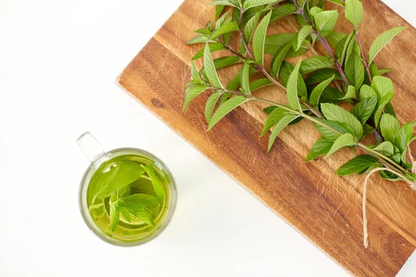 Chá de ervas com hortelã-pimenta fresca na tábua de madeira — Fotografia de Stock