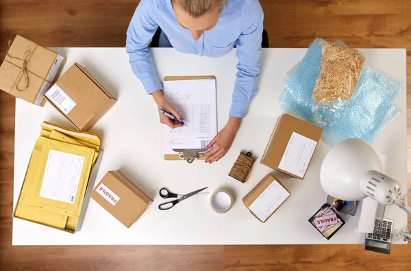 Femme avec presse-papiers et colis au bureau de poste — Photo