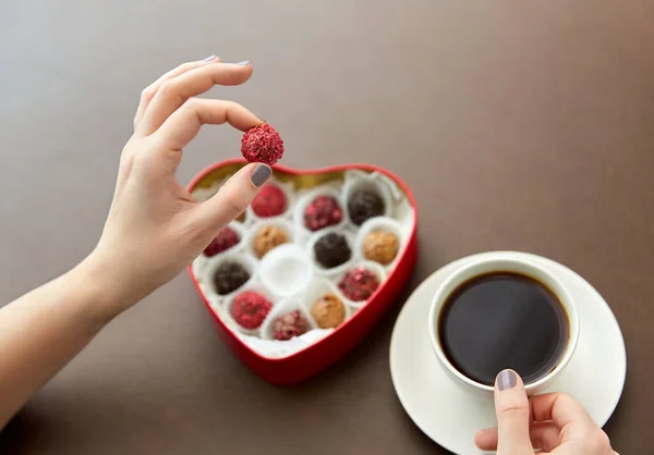 Mani, caramelle in scatola a forma di cuore e tazza di caffè — Foto Stock