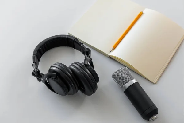 Headphones, microphone and notebook with pencil — Stock Photo, Image