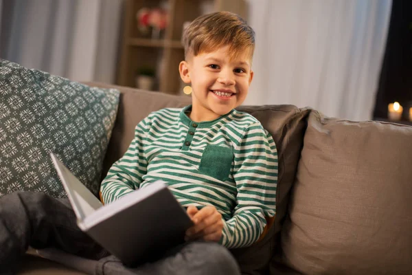 Šťastný usměvavý malý chlapec čtení knihy doma — Stock fotografie