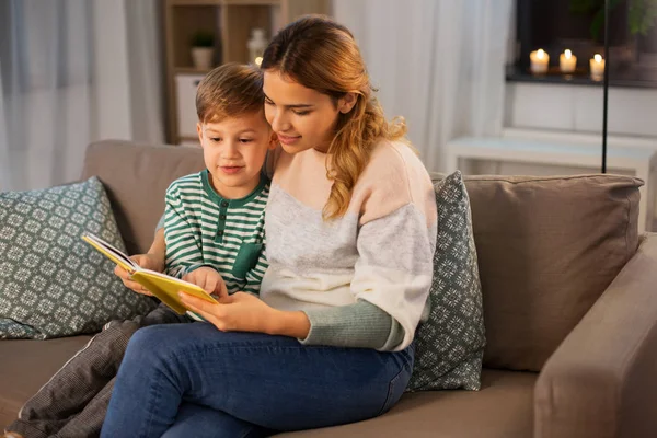 Gelukkig moeder en zoon lezen boek bank thuis — Stockfoto