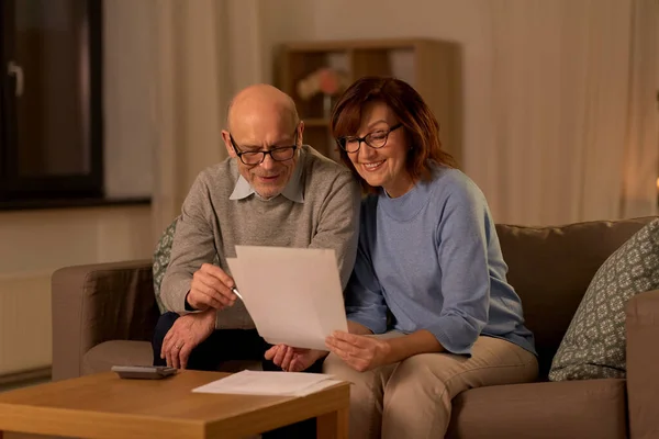 Äldre par med papper och kalkylator hemma — Stockfoto