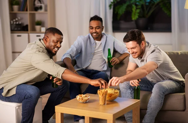 Amigos do sexo masculino beber cerveja com batatas fritas em casa — Fotografia de Stock