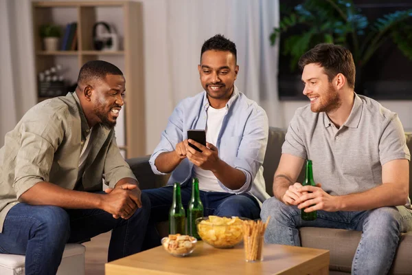 Amigos do sexo masculino com smartphone beber cerveja em casa — Fotografia de Stock
