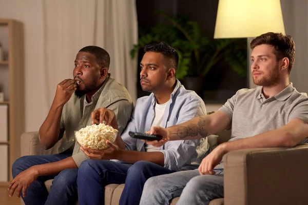 Чоловічі друзі з попкорном дивитися телевізор вдома — стокове фото