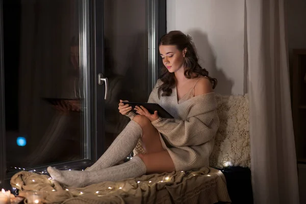 Vrouw met tablet pc zittend op vensterbank thuis — Stockfoto