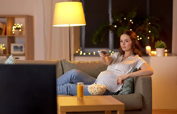 Zwangere vrouw met afstandsbediening kijken tv — Stockfoto
